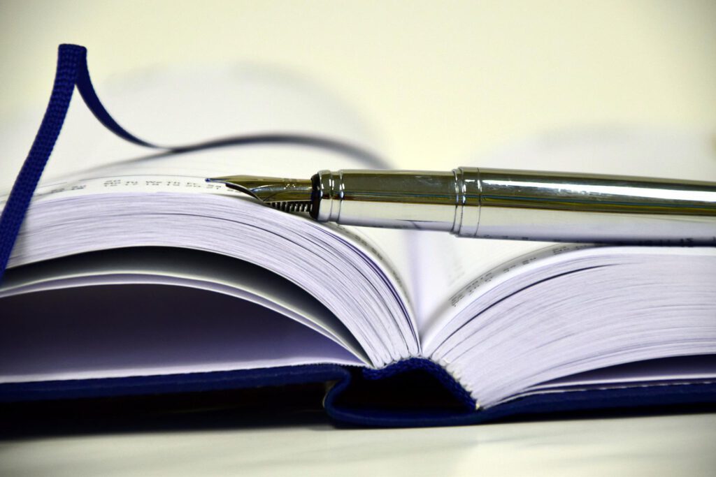 Lambda Wortmanufaktur, blaues Buch mit Lesezeichen und Füller